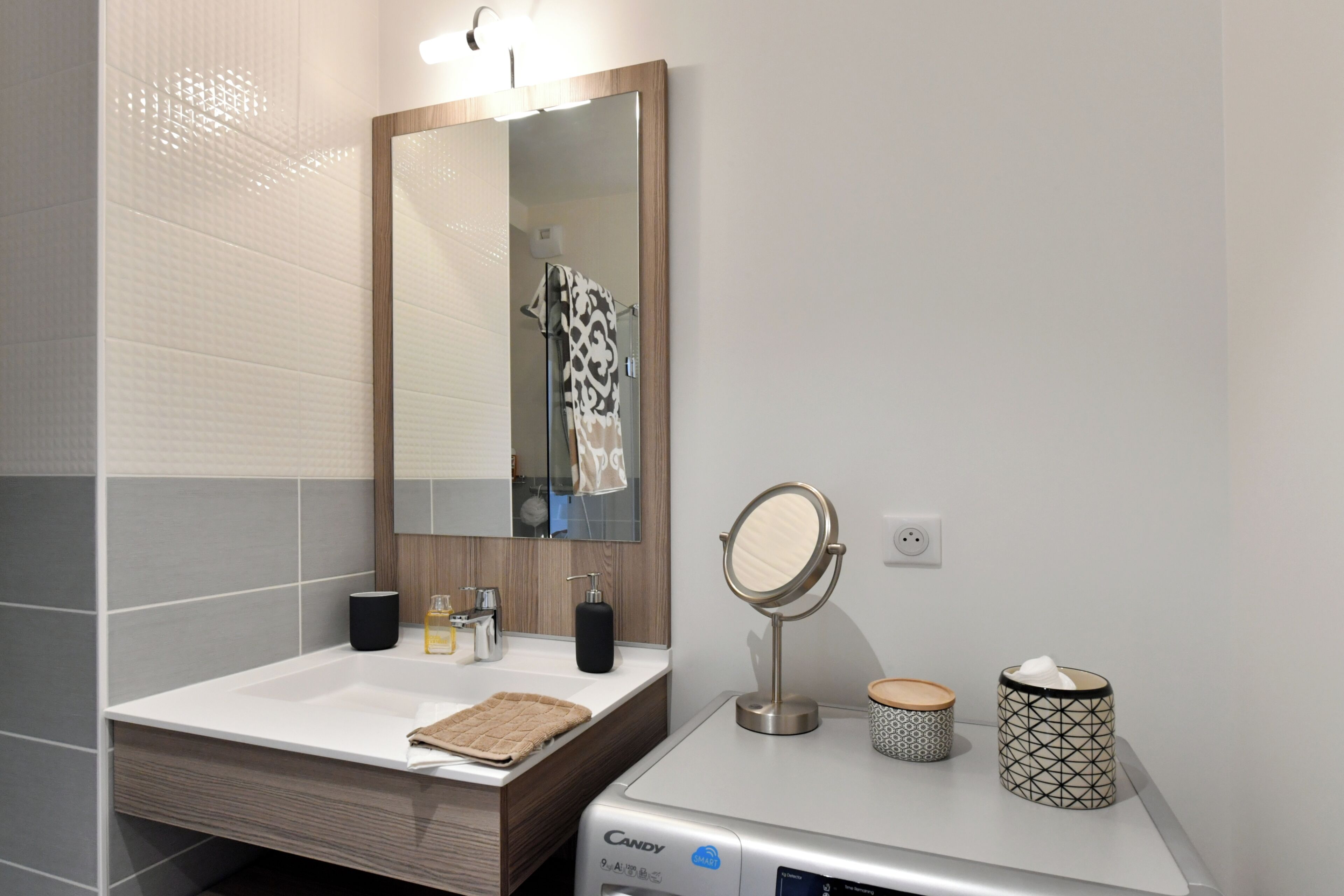 A bathroom with a white sink, a mirror, a towel, a soap dispenser, and a tissue box.