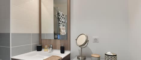 A bathroom with a white sink, a mirror, a towel, a soap dispenser, and a tissue box.