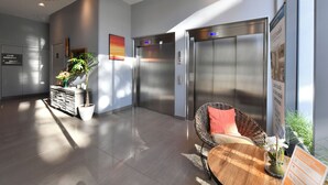 A modern lobby with two elevators, a reception desk, and a seating area with a plant and a vase. - Zenao Appart'hôtels Massy (Massy)