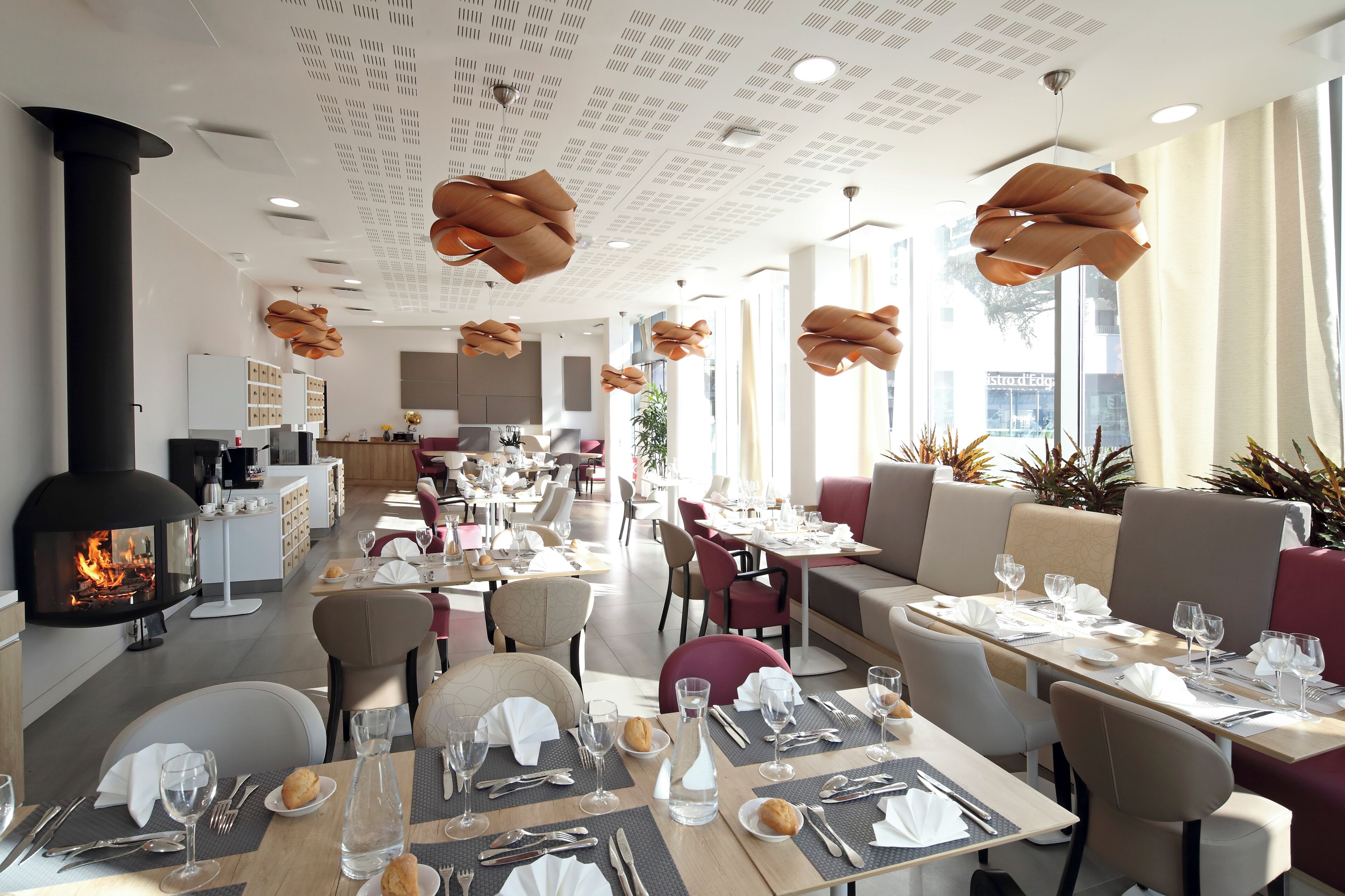 Een restaurant met een houtgestookte oven, modern meubilair en grote ramen.