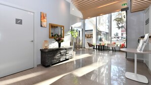 A modern lobby with a reception desk, a large mirror, and a potted plant. - Zenao Appart'hôtels Massy (Massy)