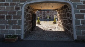 Ein Gebäude aus Stein mit einem zentralen Bogen, der in einen Innenhof führt.