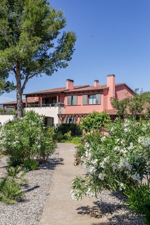 A two-story house with a red-tiled roof, a covered patio, and a gravel pathway leading to the entrance. - Apartment Gran Terraza Exclusive Costa Dorada (Bonmont Terres Noves)