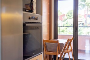 A kitchen with a built-in oven and a dining area with two wooden chairs. - Apartment Gran Terraza Exclusive Costa Dorada (Bonmont Terres Noves)