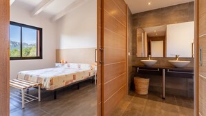 A bedroom with a bed, a nightstand, a window with a view, and a bathroom with a sink and mirror. - Apartment Gran Terraza Exclusive Costa Dorada (Bonmont Terres Noves)