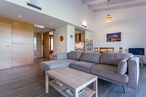 A modern living room with a sectional sofa, a wooden coffee table, and a dining area with a TV. - Apartment Gran Terraza Exclusive Costa Dorada (Bonmont Terres Noves)