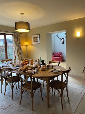 Un coin repas comprenant une table ronde, des chaises, une lampe et une décoration représentant une tête de cerf.