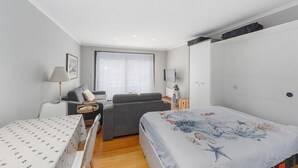 Een moderne slaapkamer met een bed, een slaapbank, een stoel, een tafel en een televisie.