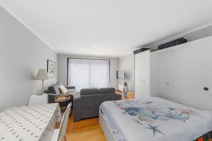 Ein modernes Schlafzimmer mit einem Bett, einem Sofa, einem Sessel, einem Tisch und einem Fernseher.