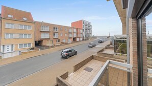 Een woonstraat met meer verdiepingen tellende gebouwen, een heldere lucht en een geparkeerde auto.