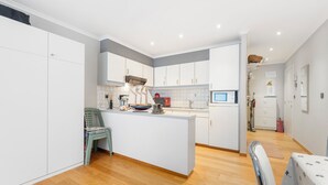Een moderne keuken met witte kasten, een centraal eiland en houten vloeren.