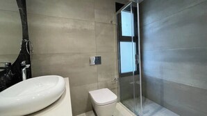 Ein Badezimmer mit weißem Waschbecken, Toilette und Duschkabine aus Glas.