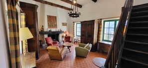 A room with a fireplace, red armchairs, a green armchair, a wooden table, and a staircase. - Set in a quiet, green location, a charming Provençal country house (Annot)