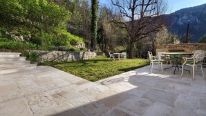 A stone patio with outdoor furniture, a stone staircase, and a view of a mountainous landscape. - In a quiet, green setting, pretty Provencal country house (Annot)