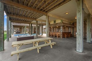 Un espace extérieur abrité comprenant une table de pique-nique en bois, un jacuzzi et un coin bar.