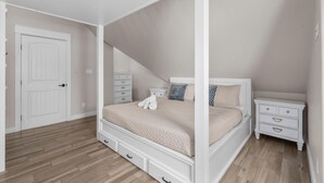 A bedroom with a four-poster bed, a nightstand, a dresser, and a door. - Beachfront | 6BR | Sleeps 33 | Hot Tub | Pickleball (Crystal Beach)