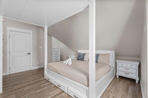 Un dormitorio con cama con dosel, mesita de noche, cómoda y una puerta.