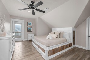 Ein Schlafzimmer mit Bett, Deckenventilator, Kommode und Fenster.