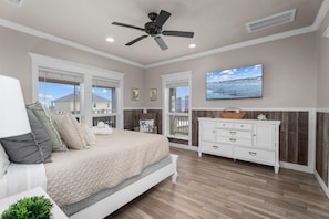 A bedroom with a bed, a ceiling fan, a TV, and a dresser. - Beachfront | 6BR | Sleeps 33 | Hot Tub | Pickleball (Crystal Beach)