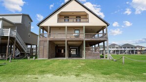 A two-story building with a balcony, a covered entrance, and a staircase leading to an upper level. - Beachfront | 6BR | Sleeps 33 | Hot Tub | Pickleball (Crystal Beach)