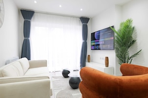 Una sala de estar moderna con un sofá, un sillón, una mesa de centro y una planta grande en maceta.