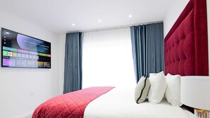 Una camera d'albergo con un letto, una TV a parete e tende.