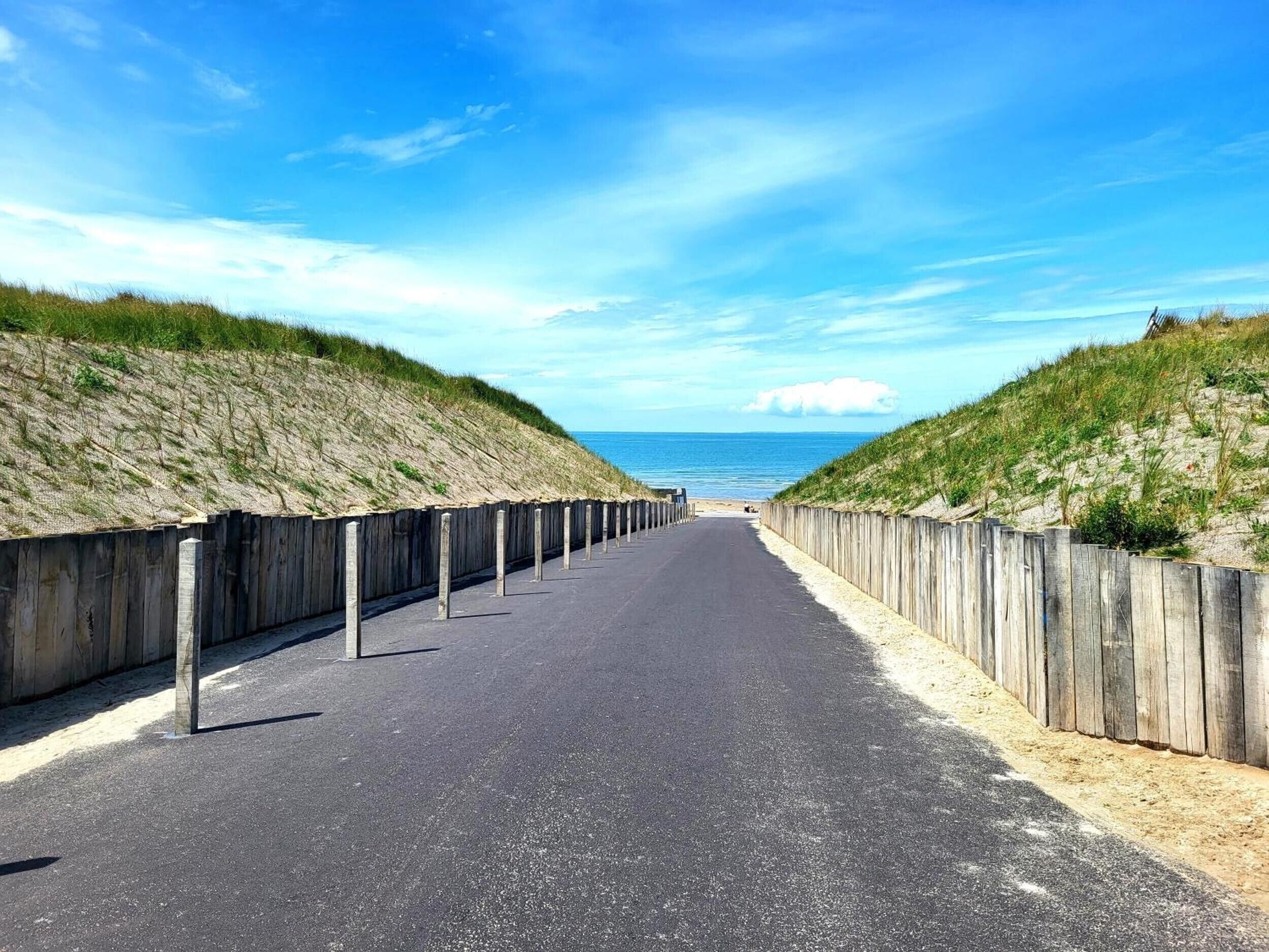 A coastal road with wooden barriers and a clear view of the ocean.