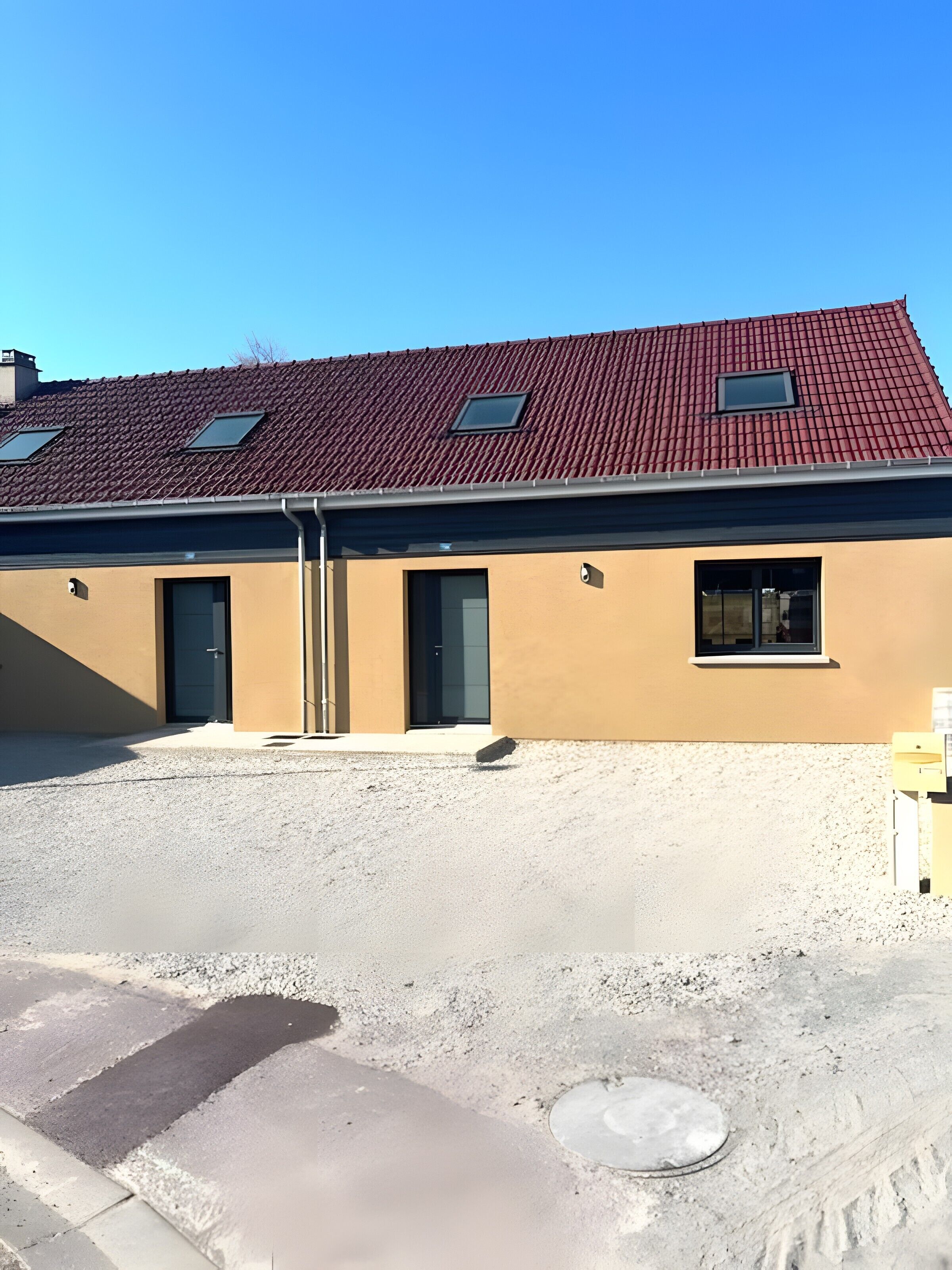 Un bâtiment avec un toit recouvert de tuiles rouges, deux fenêtres et une porte.