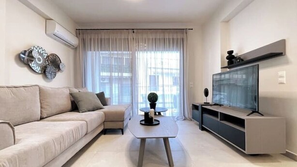 Una sala de estar moderna con sofá, una mesa de centro, televisor y decoración en la pared.