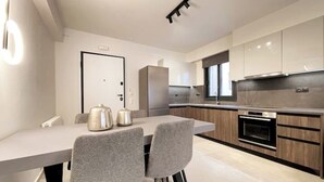 Una cocina moderna con una isla central, electrodomésticos integrados y una zona de comedor con dos sillas.