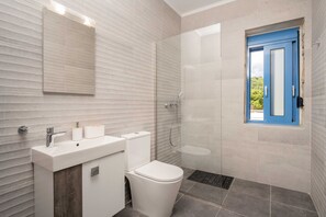 A modern bathroom with a white sink, toilet, and glass shower enclosure. - Royal Majestic Residences with Pool & Sea View (Volimes)