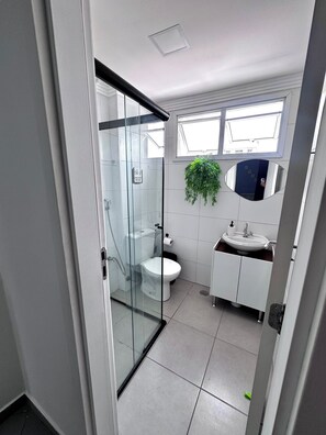 Ein modernes Badezimmer mit Duschkabine aus Glas, Toilette, Waschbecken und Spiegel.