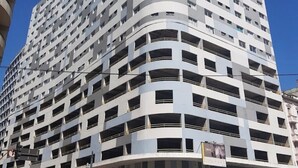 Een hotel met meerdere verdiepingen, een gebogen gevel, tal van balkons en een entree op de begane grond.