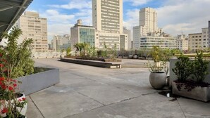 Een dak terras met plantenbakken, een zithoek en uitzicht over de stad.