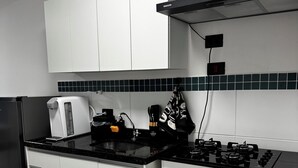 Een moderne keuken met witte kasten, een zwart aanrecht, een gasfornuis, een magnetron en een koffiezetapparaat.
