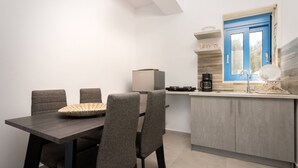 A modern kitchen with a blue door, a dining table with four chairs, and a coffee machine.