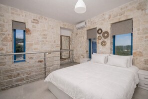 Ein Schlafzimmer mit Steinwand, einem Bett, einer Geländer und einer Aussicht.