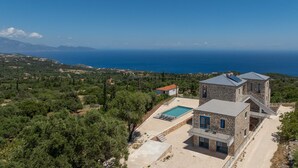 Eine Steinvilla mit Swimmingpool, einem separaten Gebäude und Blick auf Meer und Berge.