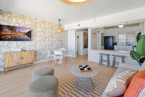 A modern living room with a flat-screen TV, a dining area, and a kitchen with bar stools. - Sea Cliff #8 | La Palma (San Diego)