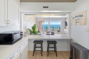 A modern kitchen with a view of the sea, a sign reading 'LA PALMA SEACLIFF California,' and a dining area with stools. - Sea Cliff #8 | La Palma (San Diego)