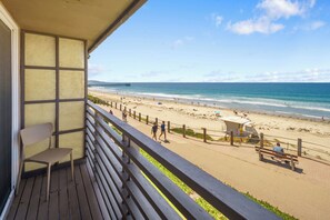 Een balkon met uitzicht op een strand, een badwachttoren en een pier in de verte.