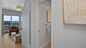 Une chambre avec vue sur la mer, une porte, un porte-serviettes et un tableau au mur.