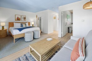 Ett modernt hotellrum med en säng, ett soffbord i trä, en soffa och ett matbord.