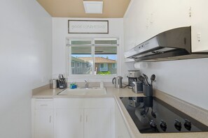 A modern kitchen with a window, a stove, and a coffee maker. - Good Vibes - Ocean Front (San Diego)