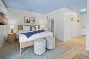 A bedroom with a bed, bedside lamps, a TV, and a cityscape view. - Good Vibes - Ocean Front (San Diego)