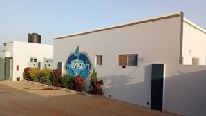 Een gebouw met een groot blauw ruitvormig bord, een klein raam en een deur.