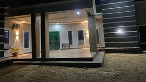 Een modern huis met een overdekte patio, een groene deur en een trap naar de bovenverdieping.