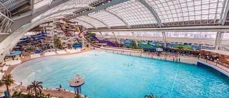Parque acuático interior con una piscina grande, toboganes y una zona cubierta.