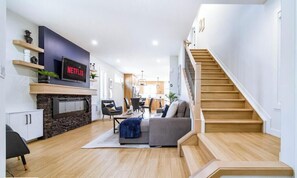 Una sala de estar moderna con chimenea, una escalera y un comedor.