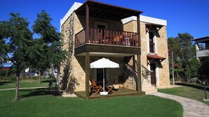 A two-story building with a balcony, outdoor seating, and a stone facade.